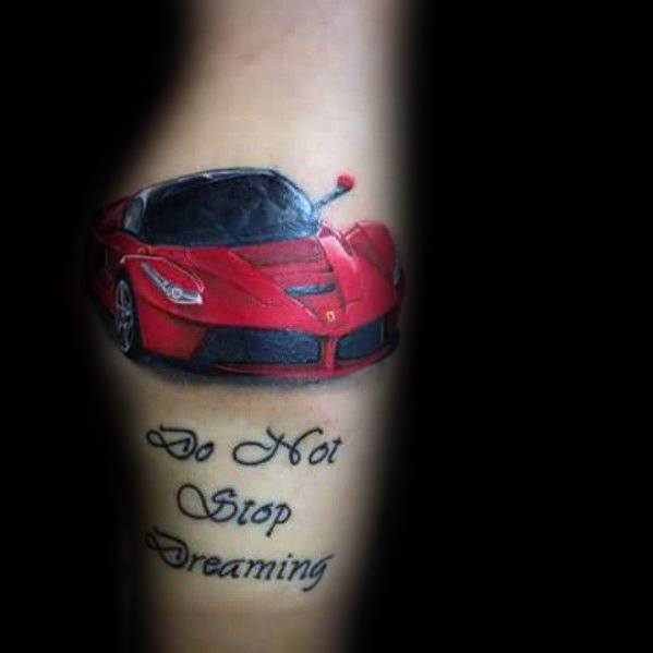 Red Ferrari tattoo with inspirational quote "Do Not Stop Dreaming" on man's arm, symbolizing ambition and aspiration for success.