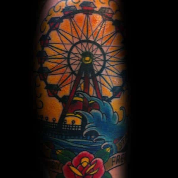 Vibrant Ferris wheel tattoo with a bold sunset background, crashing waves, and floral details, creating a dynamic and classic Americana-style design.