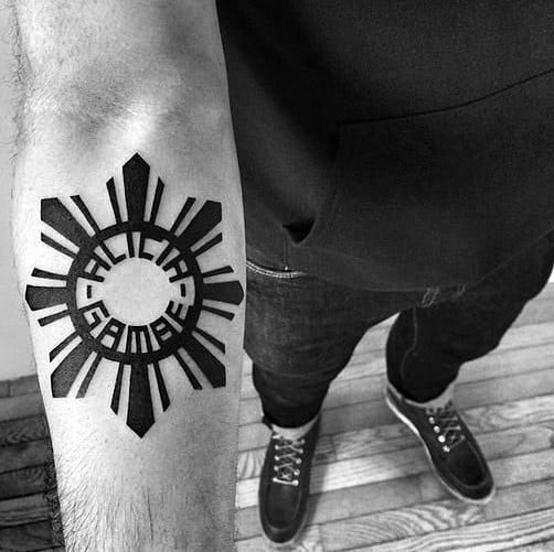 Bold Filipino sun tattoo on the forearm with thick black rays and the text “Aklan Gang” inscribed in the center circle.