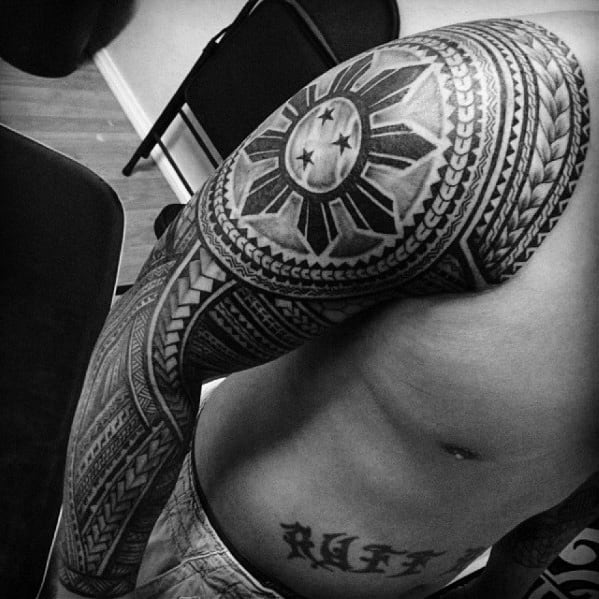 Filipino sun tattoo covering the shoulder with three stars, surrounded by intricate tribal patterns that extend into a full sleeve design.