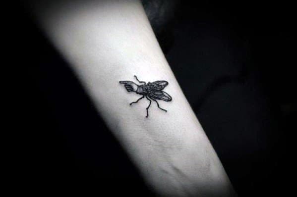 Tiny black fly tattoo with crisp linework and subtle shading, placed on the forearm for a minimalist and realistic effect.