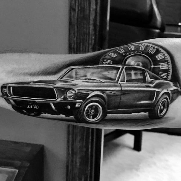 Realistic black and grey Ford Mustang tattoo on forearm, featuring a detailed classic muscle car with a speedometer background for a dynamic effect.
