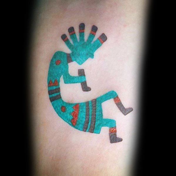 Colorful Kokopelli tattoo with turquoise body, accented by red and black tribal patterns on the arms, legs, and head, creating a lively and artistic effect.