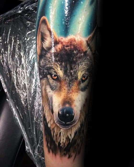 Tattoo of a wolf's head with a colorful background on an arm