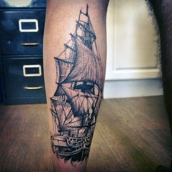 Black and grey calf tattoo of a detailed sailing ship with full sails, fine linework, and shading for a realistic maritime design