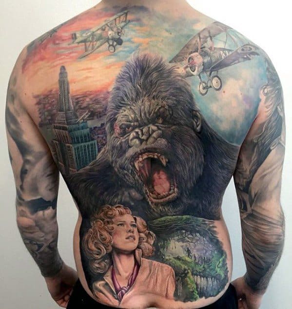 Full-color King Kong back tattoo featuring a roaring Kong, vintage planes, the Empire State Building, Skull Island, and a detailed woman portrait.