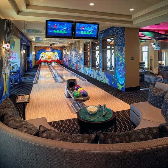 Modern bowling alley with two lanes, colorful graffiti walls, a lounge area, and overhead screens