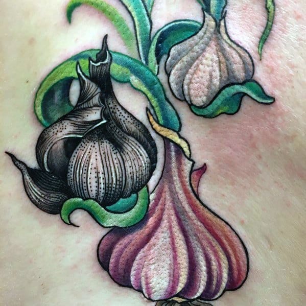 Vibrant garlic tattoo with rich shading, bold outlines, and flowing green leaves, creating a striking and artistic botanical design.
