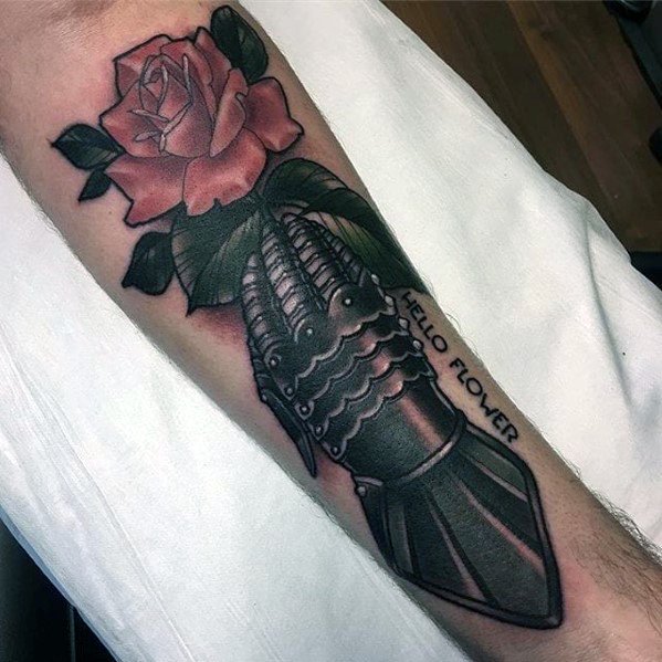 Tattoo of a metal gauntlet holding a red rose with the words "HELLO FLOWER" engraved on the wrist, blending strength and softness.