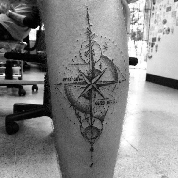Compass tattoo on calf with celestial elements, coordinates, and dotted shading, merging navigation with cosmic symbolism.