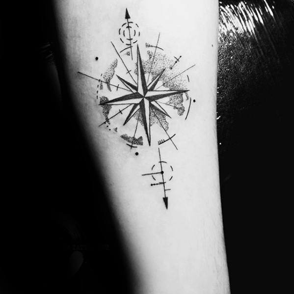 Forearm compass tattoo with bold black points, abstract elements, and dot shading, blending direction with modern artistic flair.