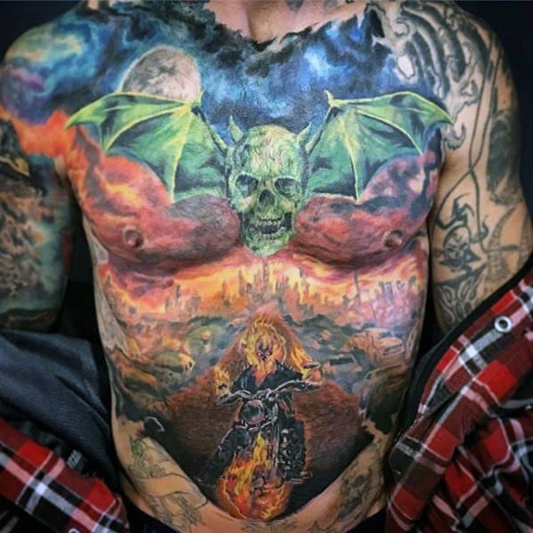 Full chest and stomach tattoo featuring Ghost Rider on a flaming motorcycle below a green-winged skull, with a fiery cityscape background.