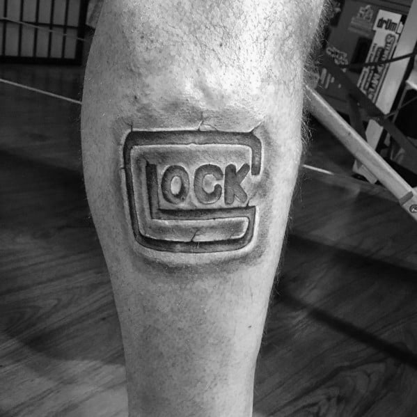 Black and grey tattoo of the Glock logo on the calf, featuring bold shading and depth to create a three-dimensional, embossed effect.