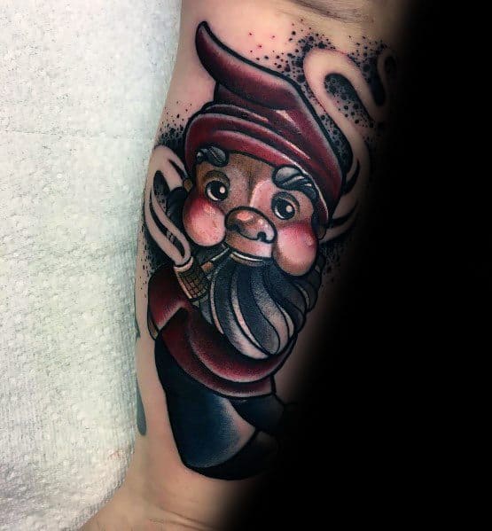 Tattoo of a playful gnome with a red hat, rosy cheeks, and a bushy beard, holding a smoking pipe with swirling smoke around him.