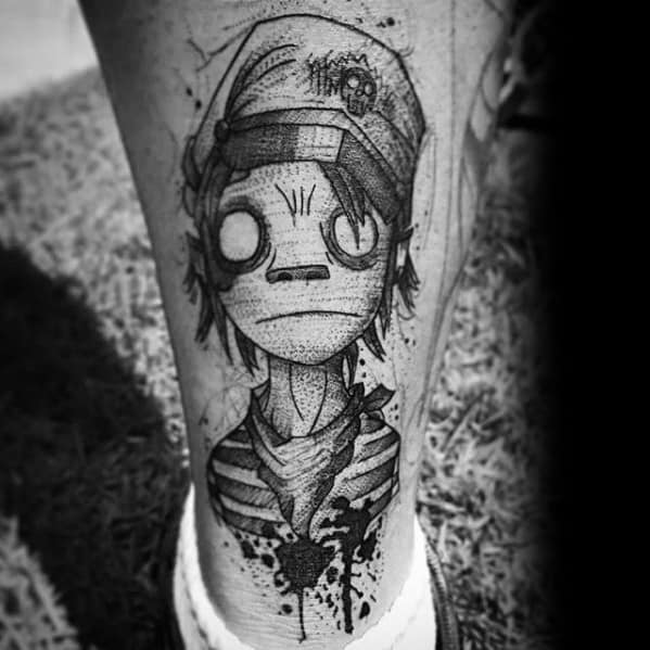 Detailed black and grey tattoo of 2D from Gorillaz with a striped shirt, beanie, and wide blank eyes, featuring sketch-style textures and shading.