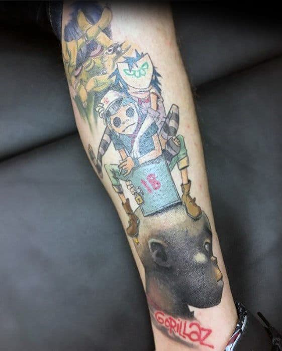 Colorful leg tattoo of Gorillaz characters with Noodle sitting on 2D’s shoulders, featuring a box labeled “18” and the Gorillaz logo below.