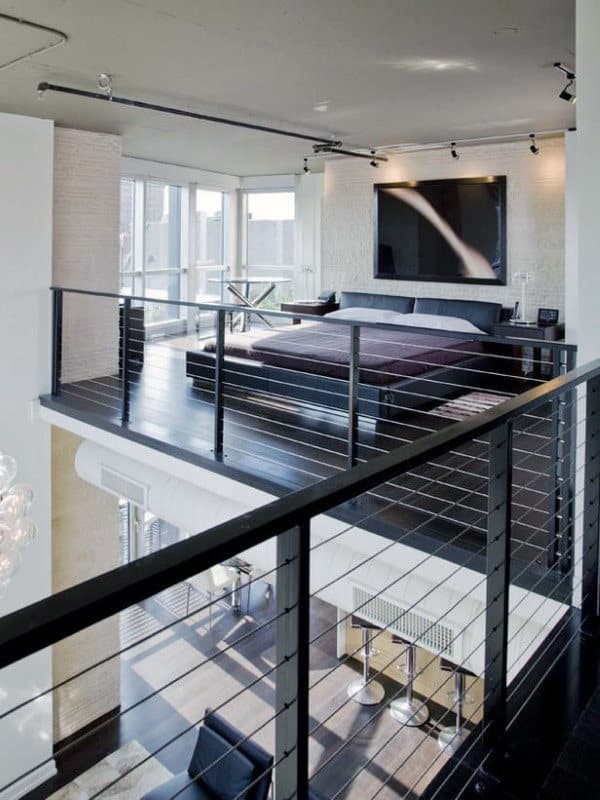 Modern loft apartment with a bedroom on an elevated platform and glass railings