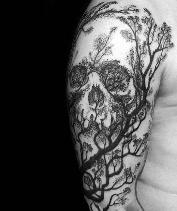 Detailed tree tattoo with fine branches and leaves forming a hidden skull pattern across the upper arm in a surreal forest design.