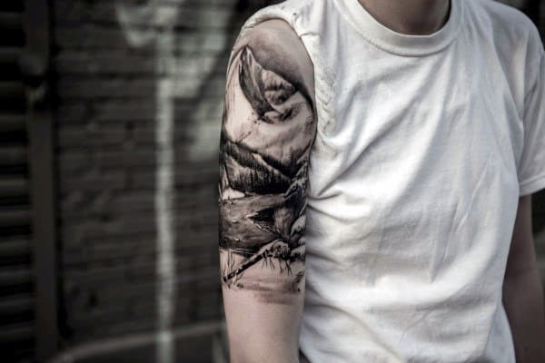 Close-up of a black and white outdoor-themed tattoo on a person's upper arm