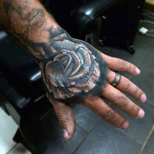 A black and gray tattoo of a detailed rose on the hand, with realistic shading and a money design subtly incorporated into the petals