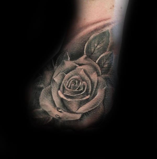 Black and gray rose tattoo with leaves on skin