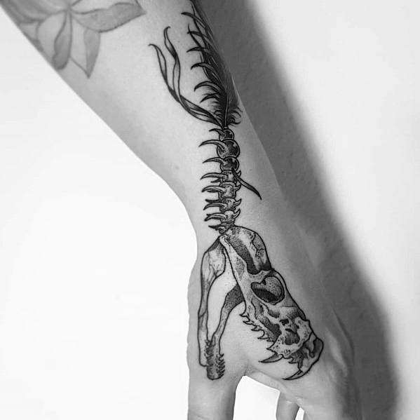 Snake skeleton tattoo on the hand and wrist, featuring a detailed skull and spine with fine linework for a bold and edgy design.