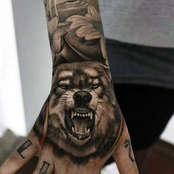Wolf tattoo with bared teeth on the back of a person's hand