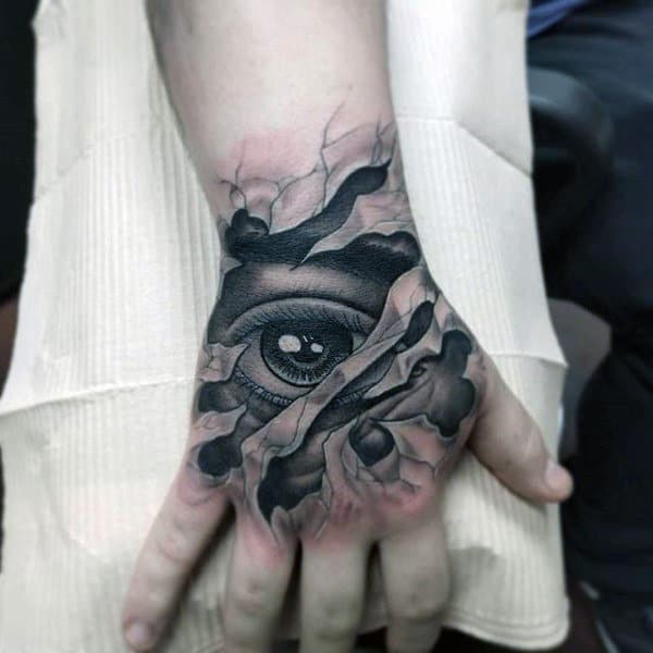 Hand tattoo featuring an eye with a cracked, ripped skin effect across the back of the hand