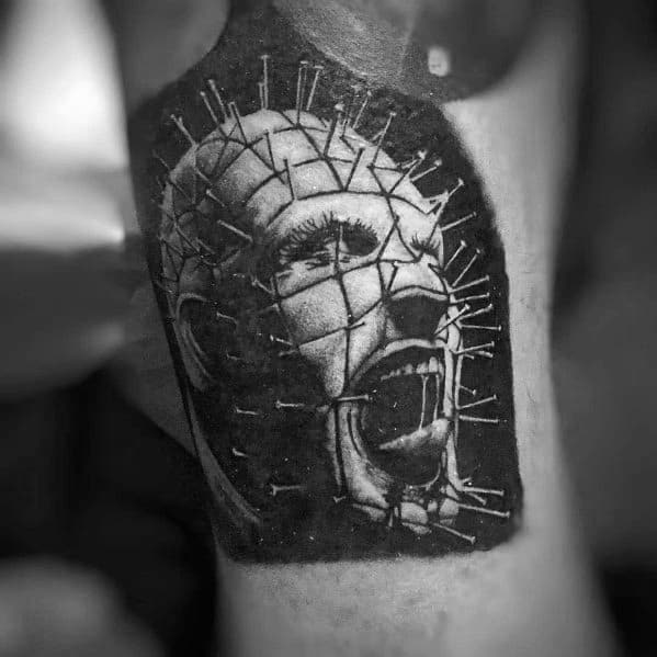 Black and grey *Hellraiser* tattoo of Pinhead screaming, featuring deep shading, intricate pin details, and a dark, intense horror aesthetic.