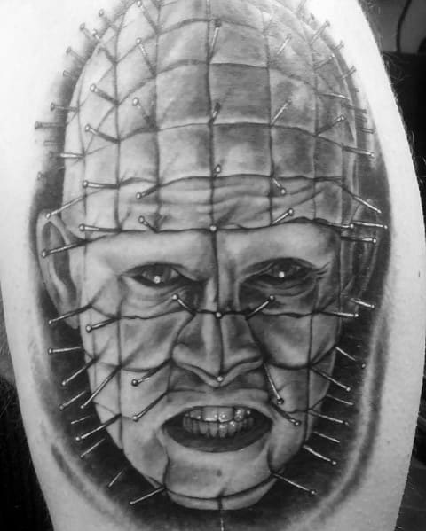 Black and grey *Hellraiser* tattoo of Pinhead with intense shading, intricate pin details, and a menacing expression for a bold horror design.