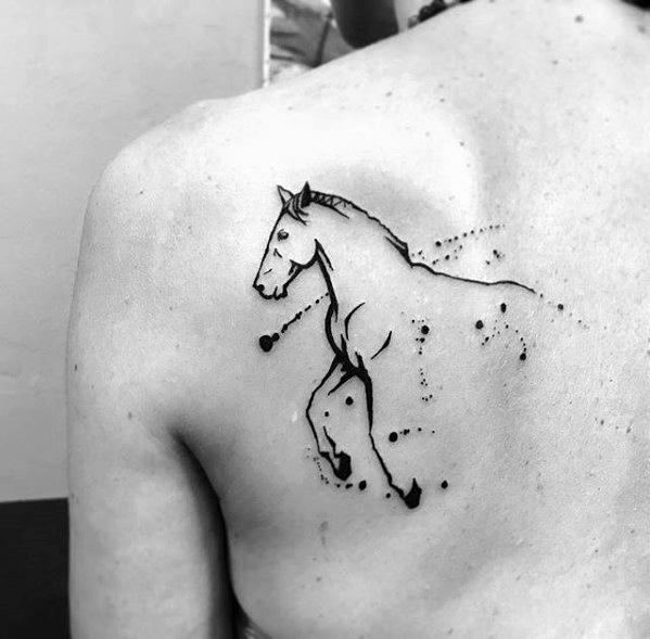 Minimalist black ink tattoo of a horse in motion on the shoulder blade, with dotted accents and abstract linework