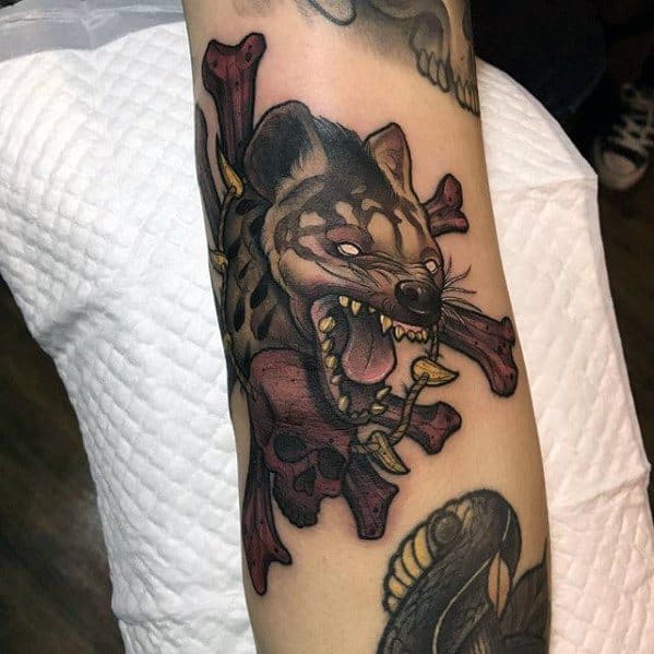 Fierce hyena tattoo with glowing eyes and sharp fangs, set against a background of dark red skulls and crossed bones for a bold, menacing look.