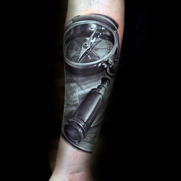 Forearm tattoo of a realistic compass and vintage telescope in black and gray