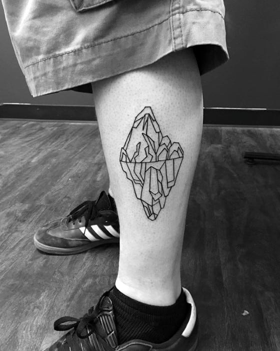 Minimalist linework iceberg tattoo on the calf, with geometric detailing above and below the waterline.