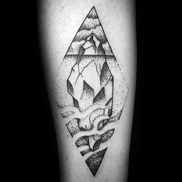 Dotwork iceberg tattoo in a diamond frame with abstract fragmented underwater shapes and a cloudy sky above.
