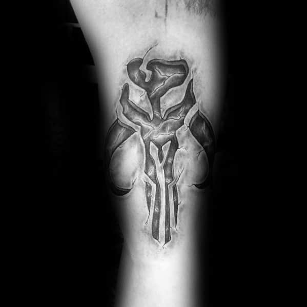 Realistic Mandalorian Mythosaur skull tattoo with deep shadows and a carved stone effect on the inner bicep.