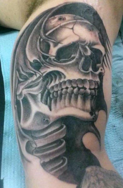 Black and grey tattoo of a detailed skull with realistic shading, featuring exposed bones and intricate highlights on the upper bicep