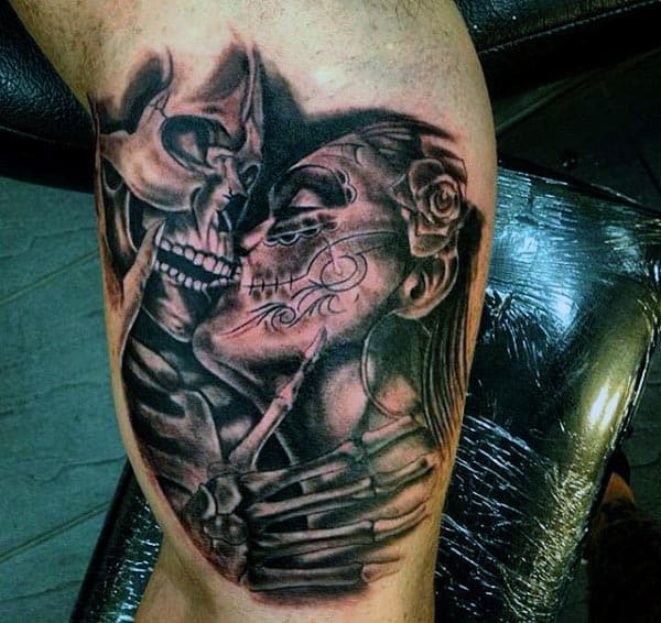 Black and grey tattoo of a skeleton kissing a woman with sugar skull makeup, featuring detailed shading and Day of the Dead elements