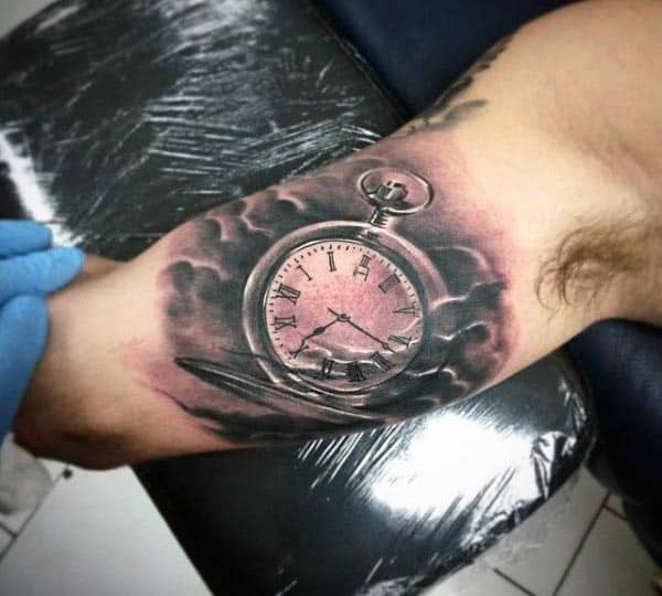 Black and grey tattoo of a detailed pocket watch with Roman numerals, surrounded by shaded clouds, creating a timeless and classic design