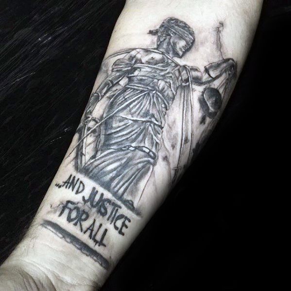 Sketch-style Lady Justice tattoo on forearm with broken scales and the phrase ...And Justice For All below, referencing Metallica’s album.