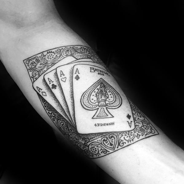 Tattoo of playing cards with aces on an arm, featuring intricate patterns