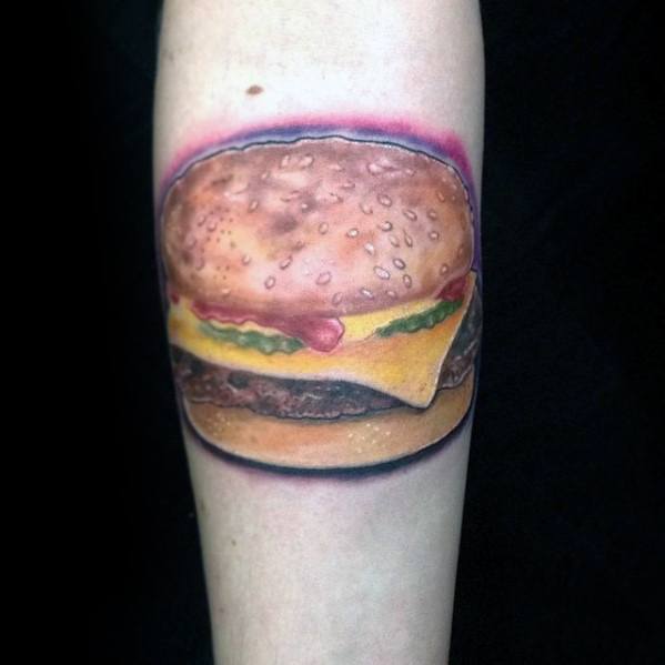 Forearm tattoo of a mouthwatering cheeseburger with lettuce, cheese, and a splash of ketchup
