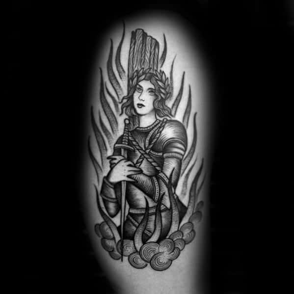 Black and grey Joan of Arc tattoo with laurel crown, sword, flames, and clouds, symbolizing her martyrdom with graceful detail.