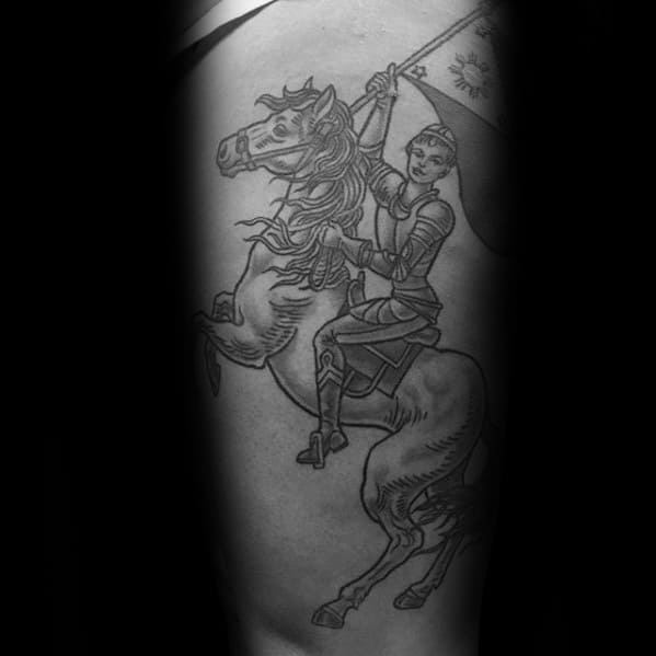 Black and grey Joan of Arc tattoo showing her riding a rearing horse, holding a flag high in a heroic and dynamic battle pose.