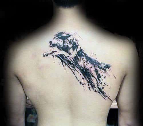 Back tattoo of a stylized, leaping black dog with artistic ink splatter design