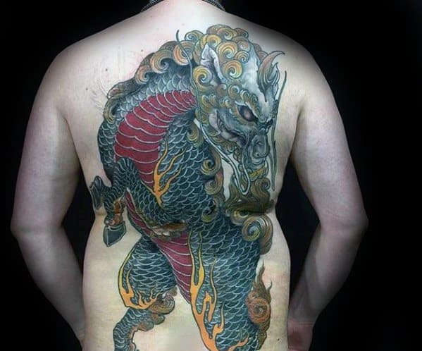Full-back Kirin tattoo with dark scales, red underbelly, golden mane, and glowing eyes, designed in a powerful and intense traditional style.