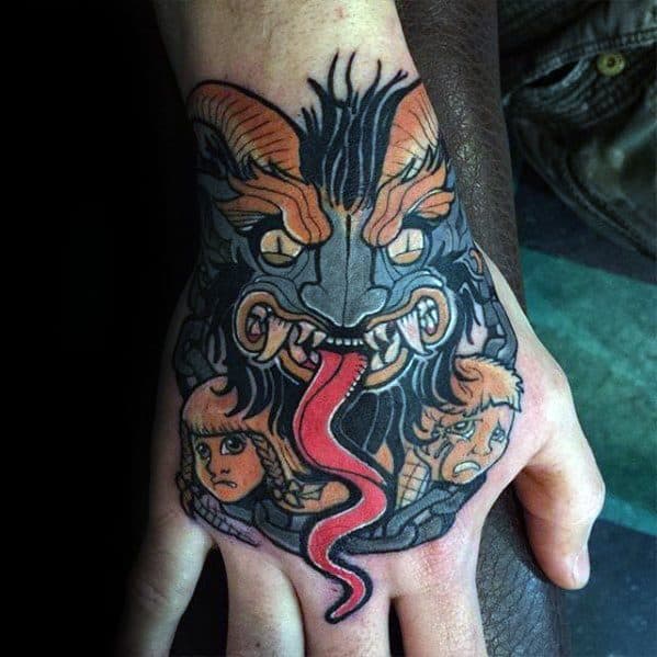 Dark Krampus hand tattoo showing a snarling horned face with glowing eyes, long red tongue, and two distressed children beneath its grip.