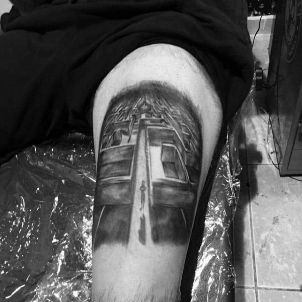 Realistic black and grey tattoo on a man's thigh, featuring a 3D perspective of a labyrinth with a lone figure walking towards its center.