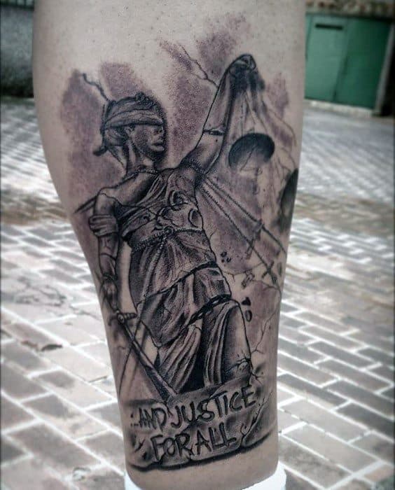 Black and grey tattoo of Lady Justice with cracked scales and the phrase ...And Justice For All, referencing Metallica’s iconic album artwork.