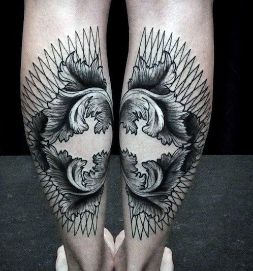 Elaborate symmetrical tattoos on the backs of two legs with floral and geometric designs